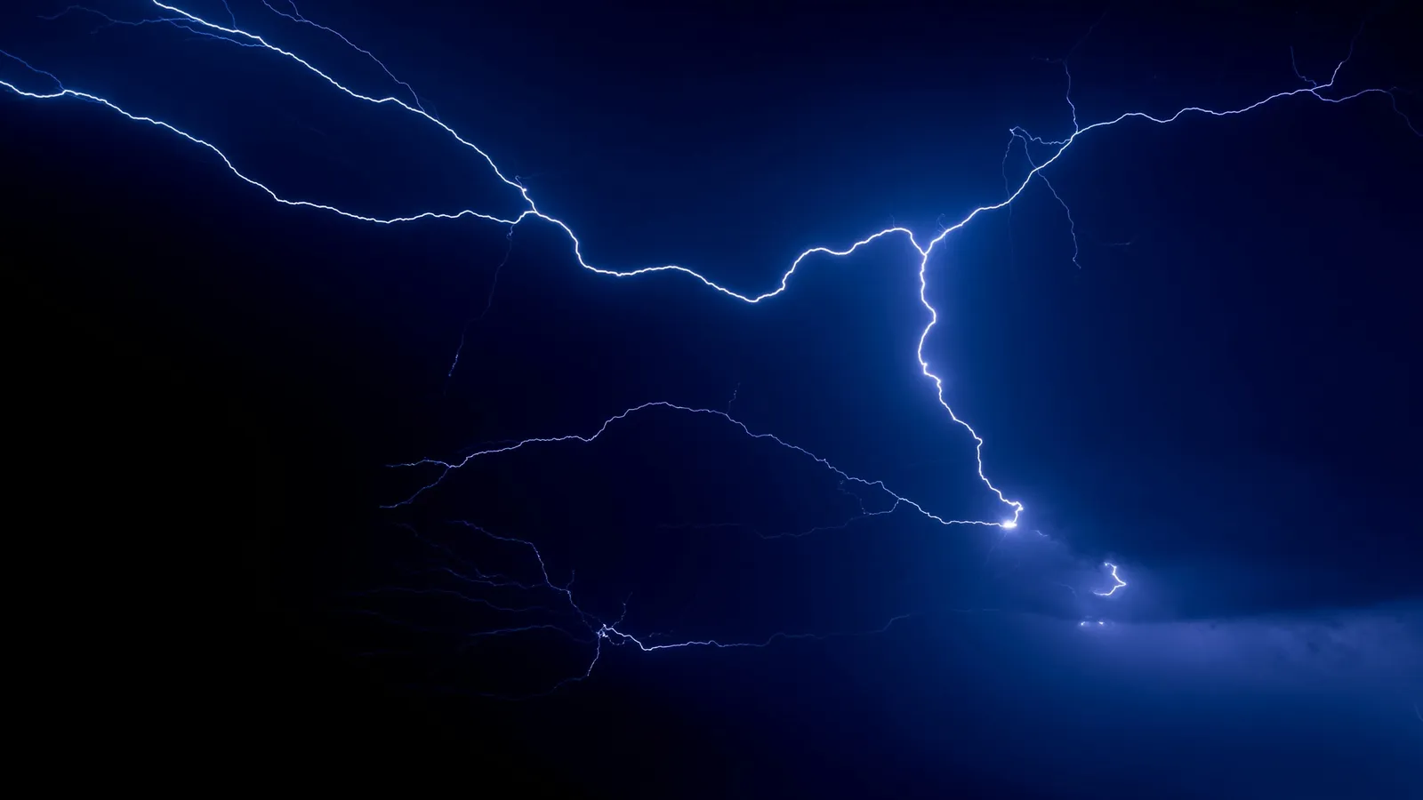 Lightning branching across a dark blue sky