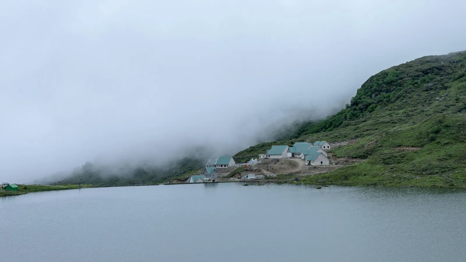 Low cloud drifting over a lake and green hills