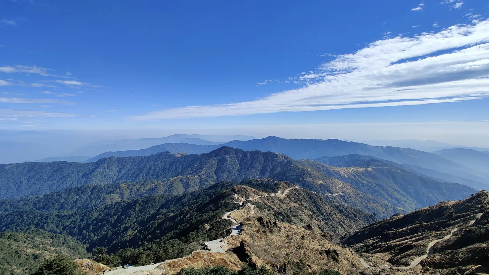 Mountain ridges under a blue sky with scattered clouds