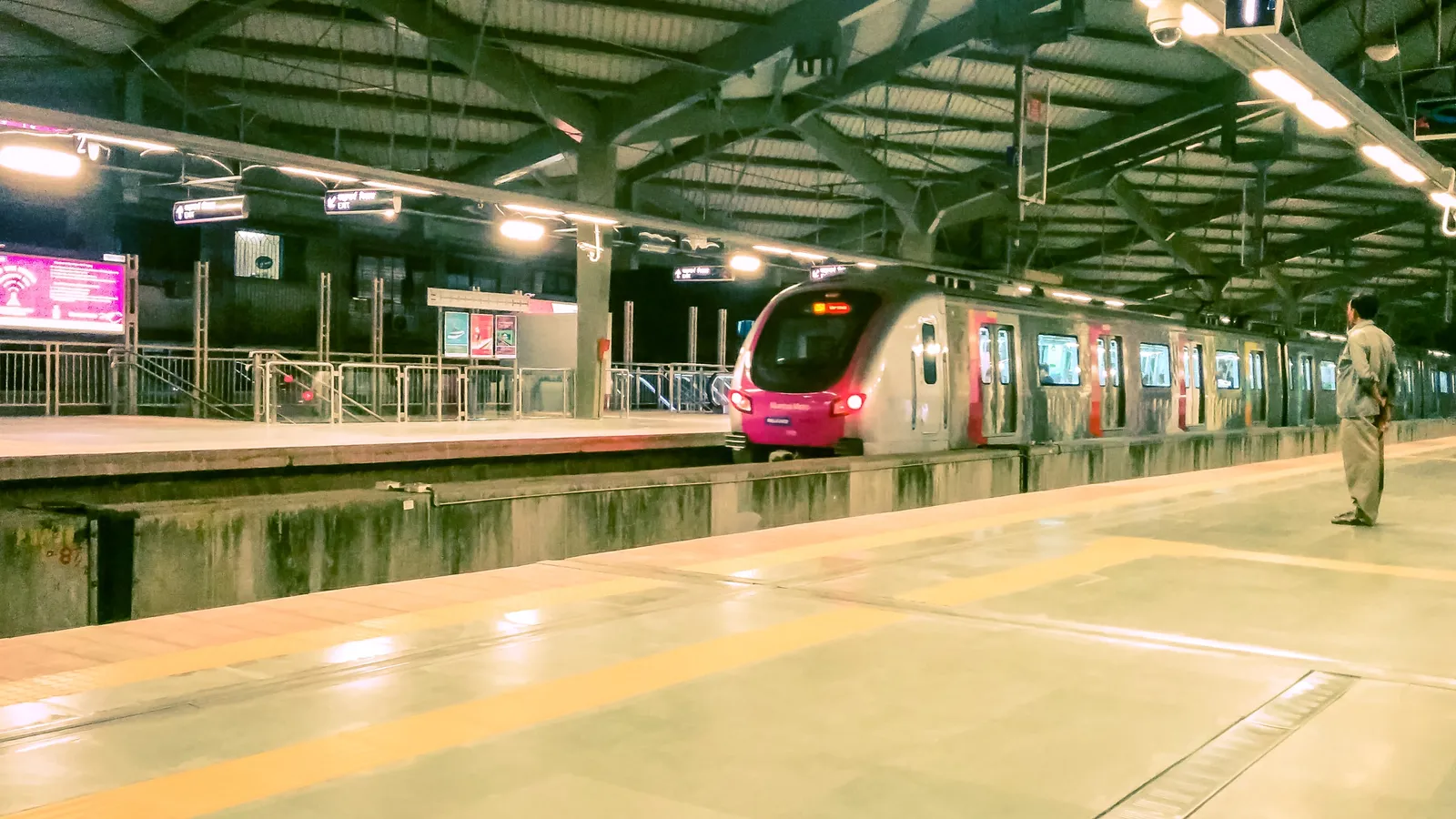 Mumbai Metro train arriving at Azad Nagar station as a man waits on the platform
