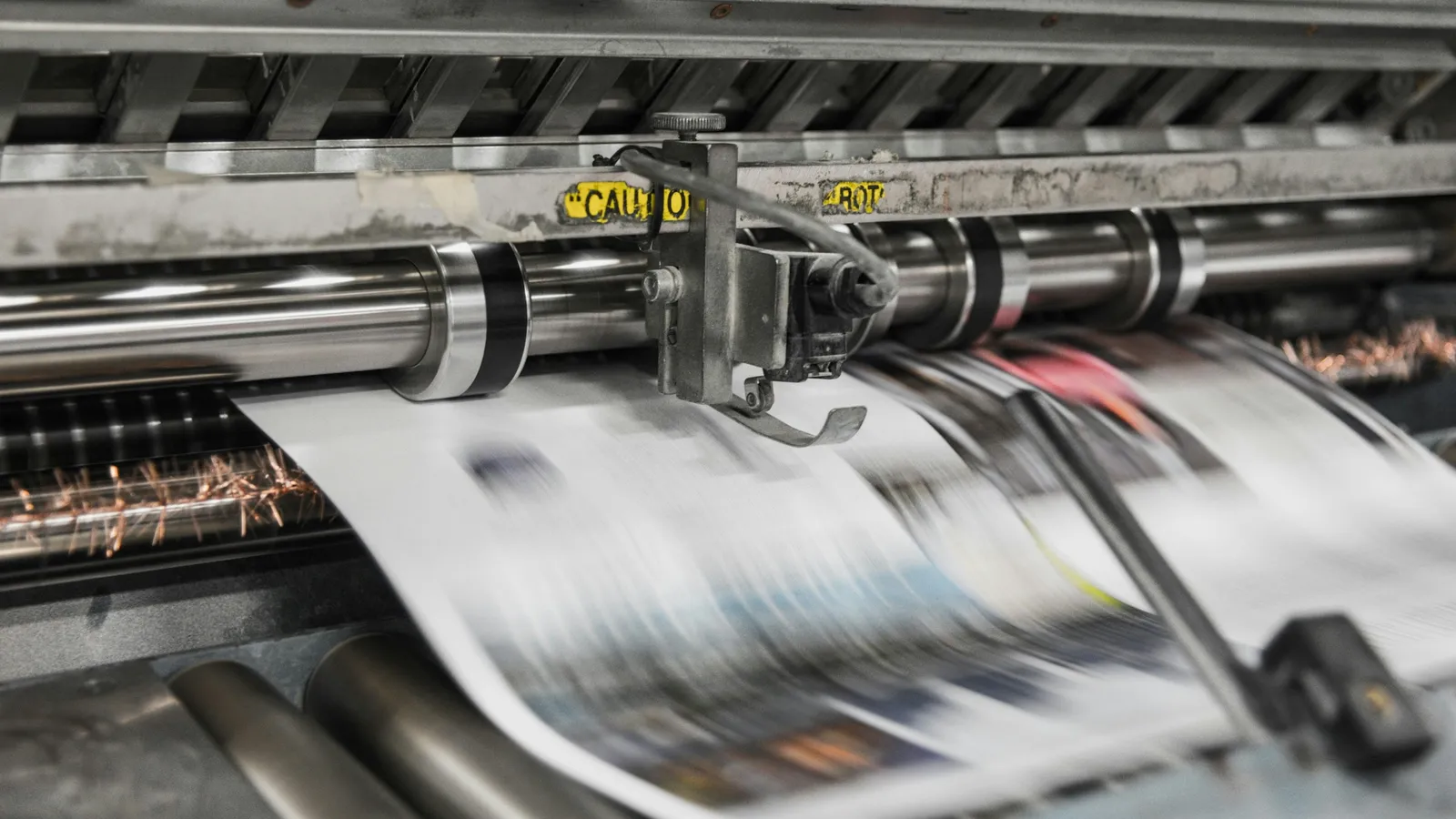 Newspaper pages running through the rollers of a printing press