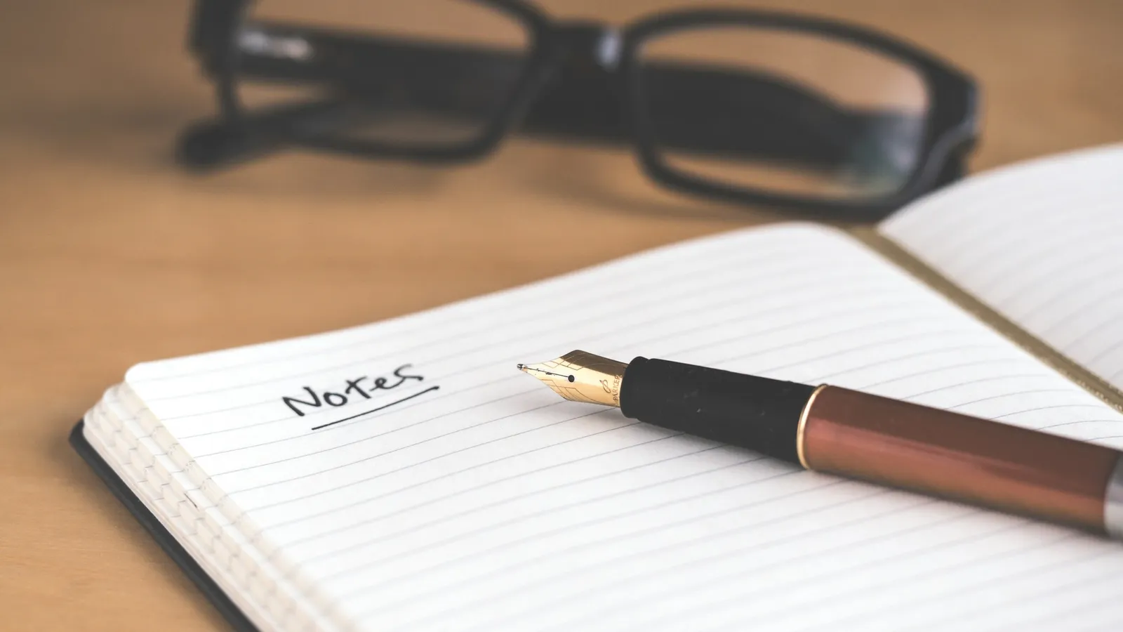 Notebook page headed Notes with a fountain pen and glasses