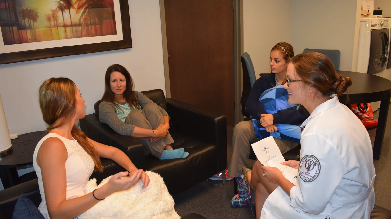 Occupational therapist in a white coat leading a small group discussion in a lounge