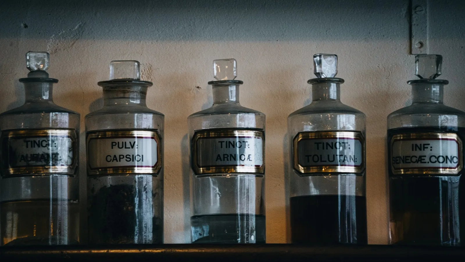 Old apothecary jars lined up on a dark shelf