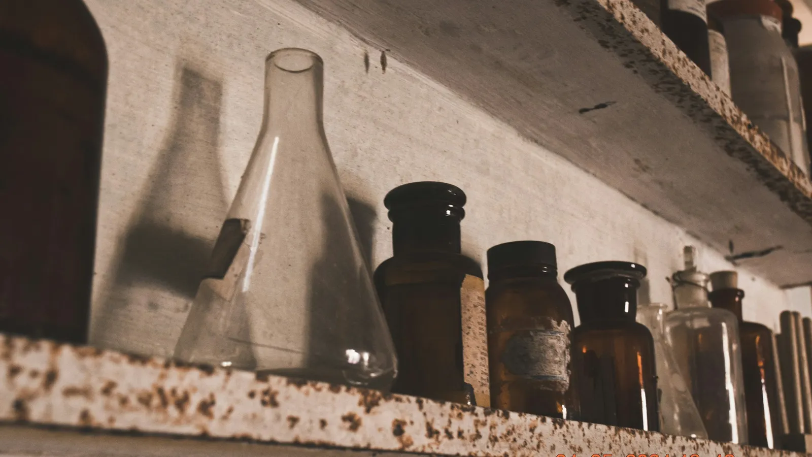 Old glass flasks and bottles on a dusty laboratory shelf