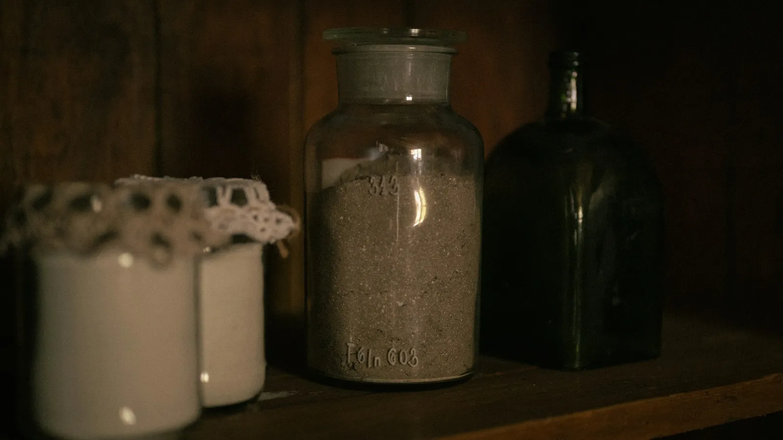 Old glass laboratory jars on a dark shelf