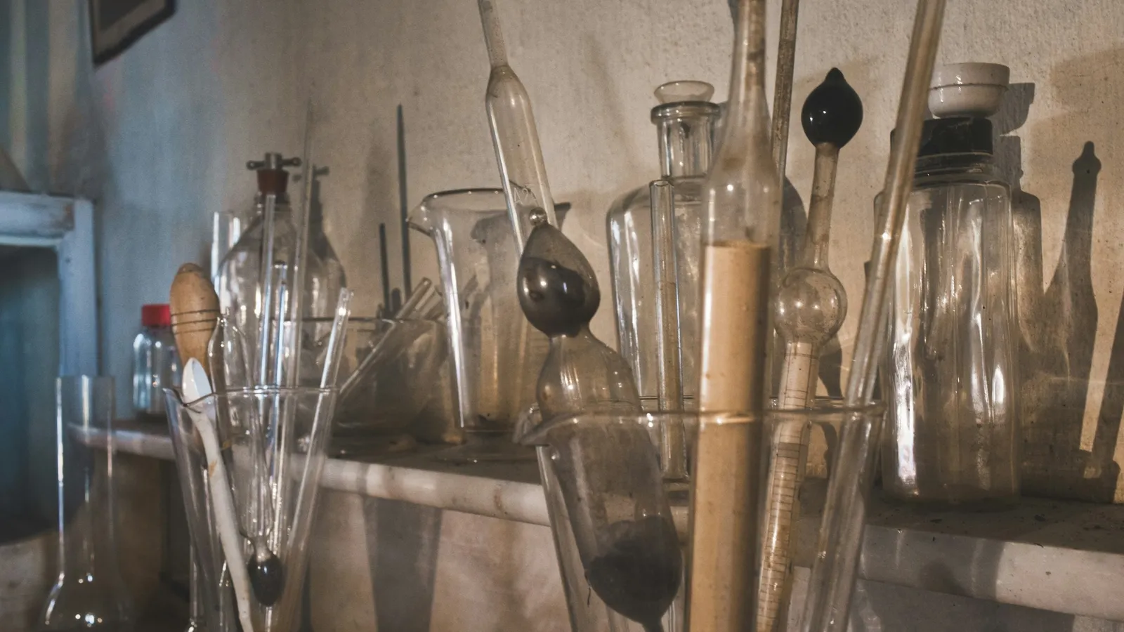 Old glassware and flasks crowded on a laboratory shelf