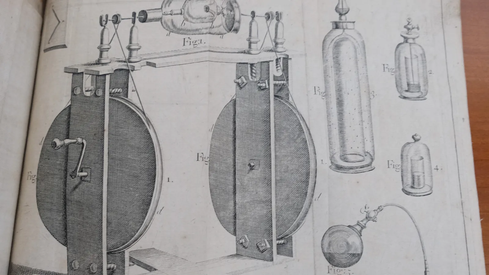 Open 1719 book showing Hauksbee's engraved wheel-driven glass globe machine and glass vessels