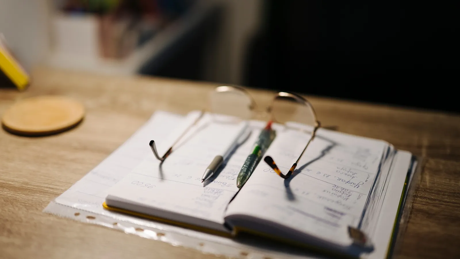 Open bound notebook with pens and glasses on punched loose sheets in a plastic sleeve
