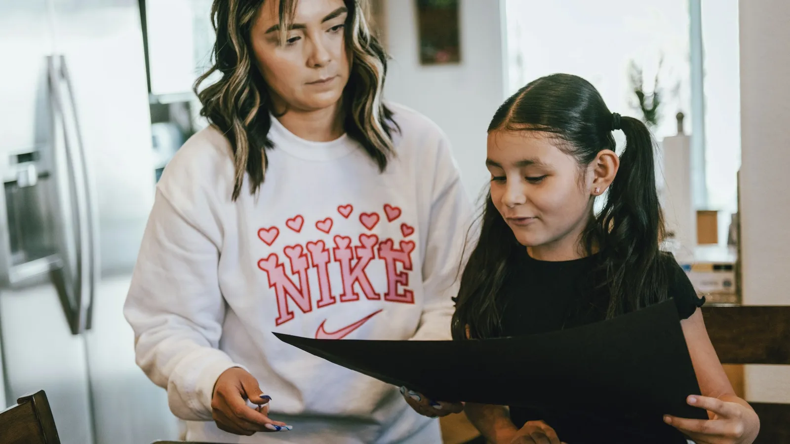 Parent and teenage daughter looking at schoolwork together