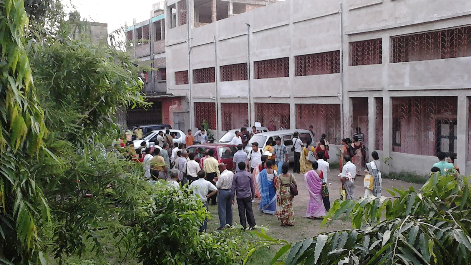 Parents and students waiting in a school courtyard outside an entrance exam centre