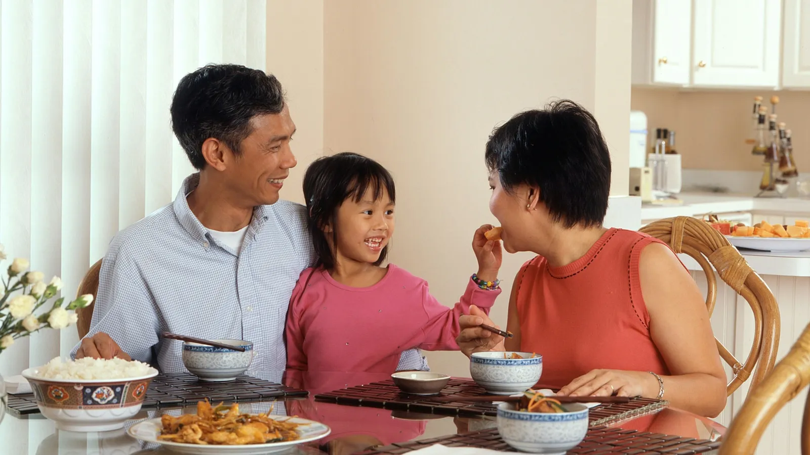 Parents and their daughter talking and laughing at the dinner table