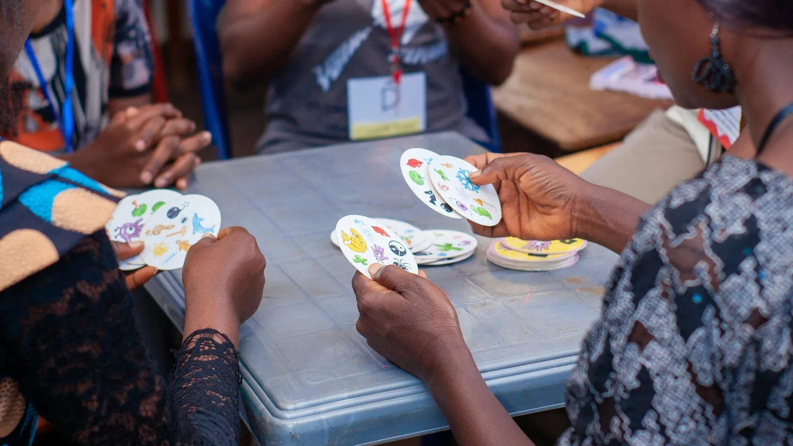 People holding playing cards around a table during a game
