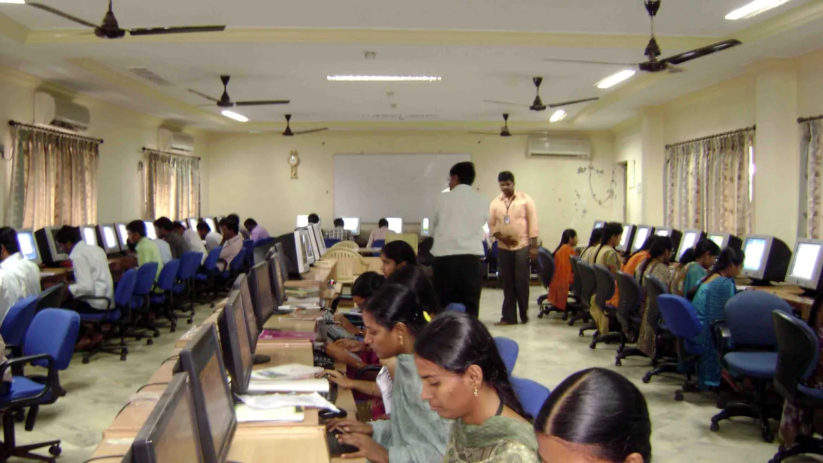 People working at rows of computers in a degree college computer lab in India