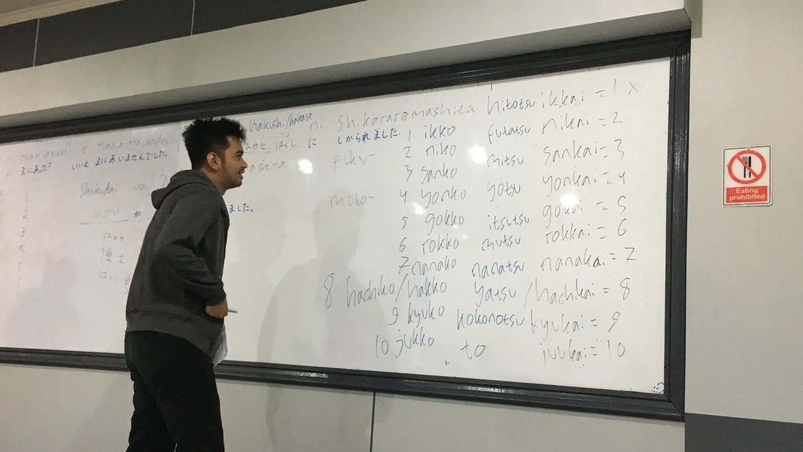 Person at a classroom whiteboard listing Japanese counting words in romaji