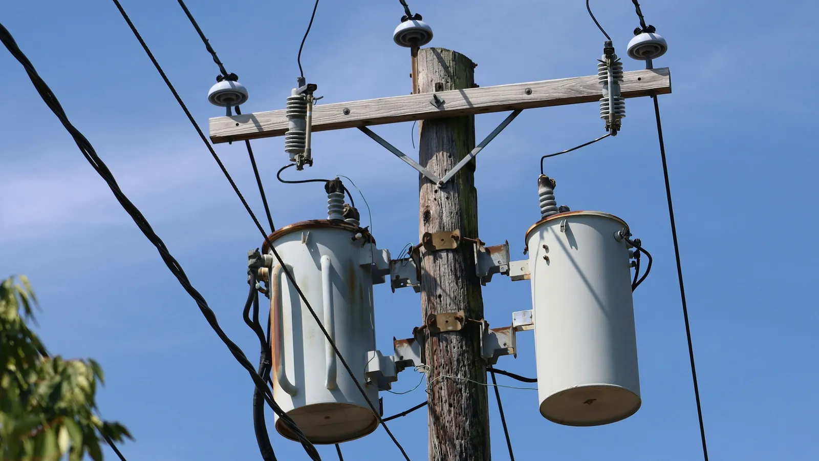 Pole-mounted electrical transformers against a blue sky