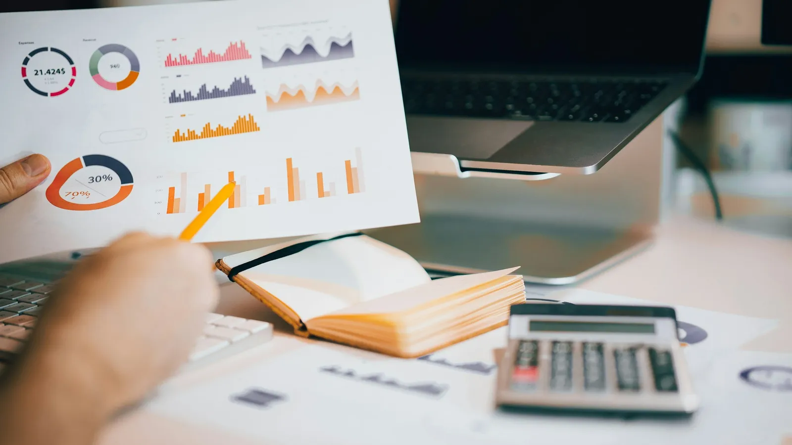 Printed bar and pie charts on a desk beside a calculator