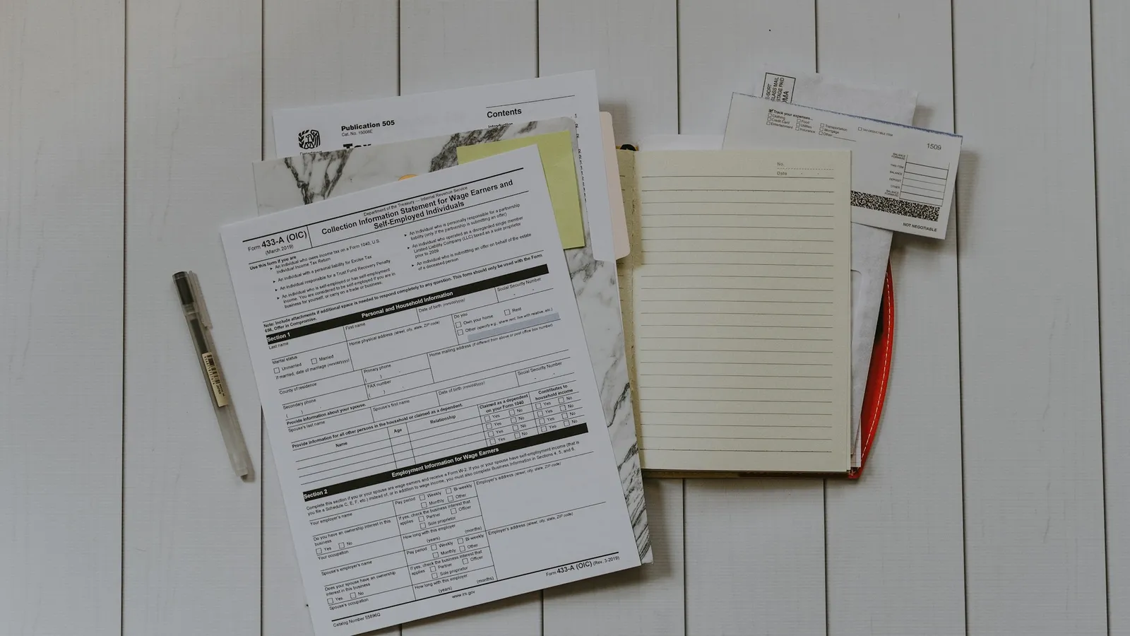 Printed forms and a notepad on a wooden table