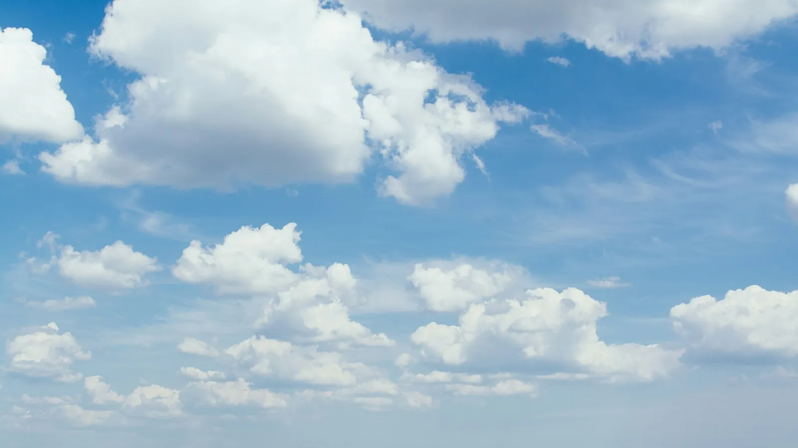 Puffy cumulus clouds over a flat green field
