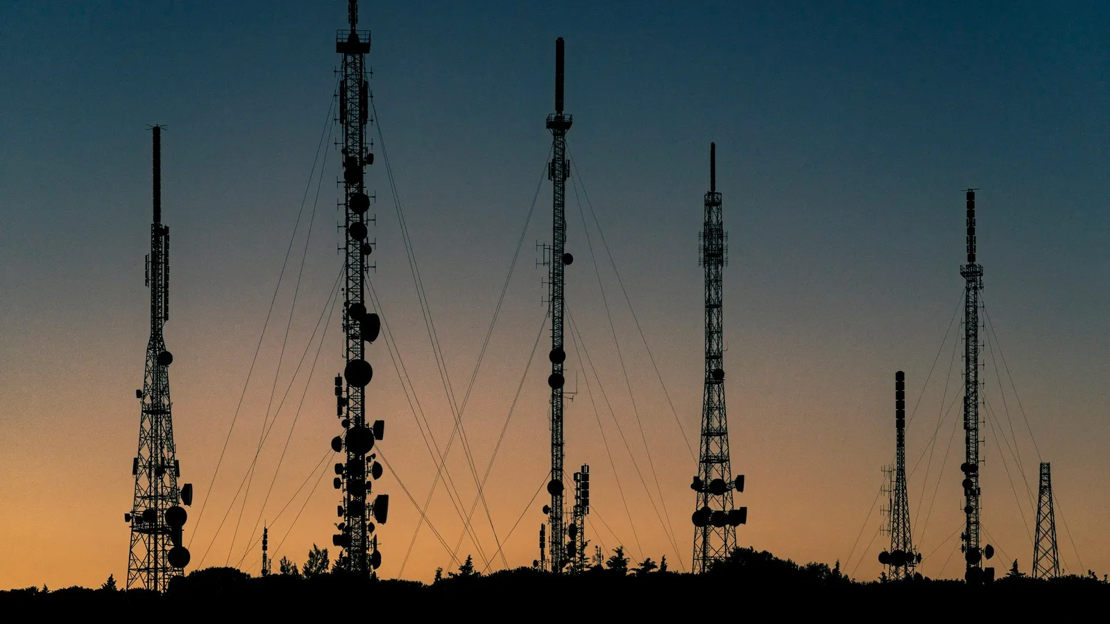 Radio masts silhouetted against an orange evening sky