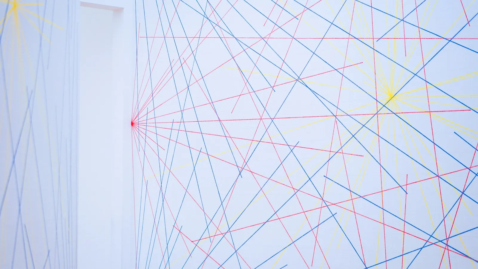 Red and blue lines crossing on a white wall