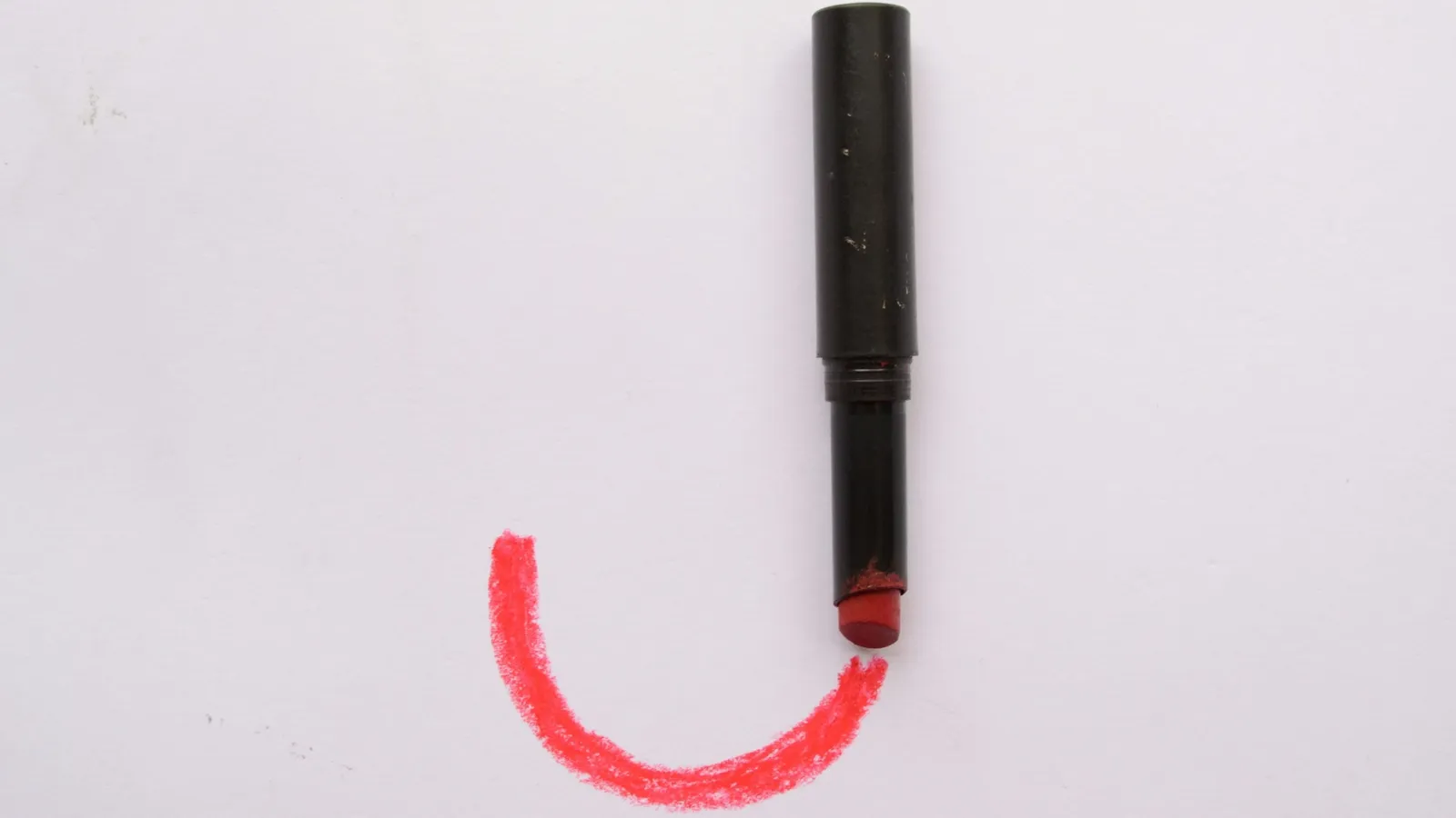 Red marker drawing a curved line on white paper