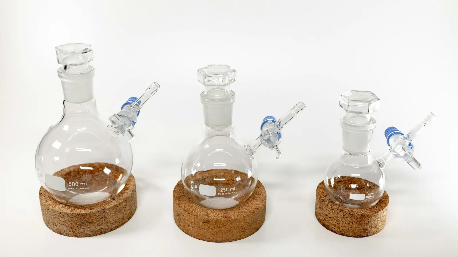 Round glass flasks on a white lab bench