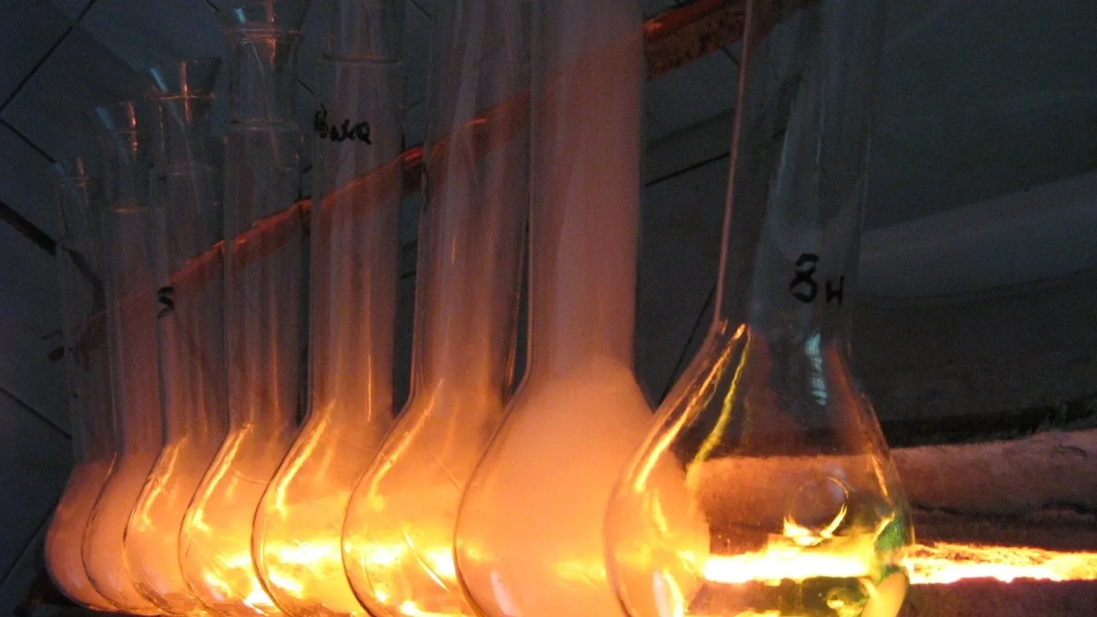 Row of long-necked Kjeldahl flasks glowing orange on a digestion heater