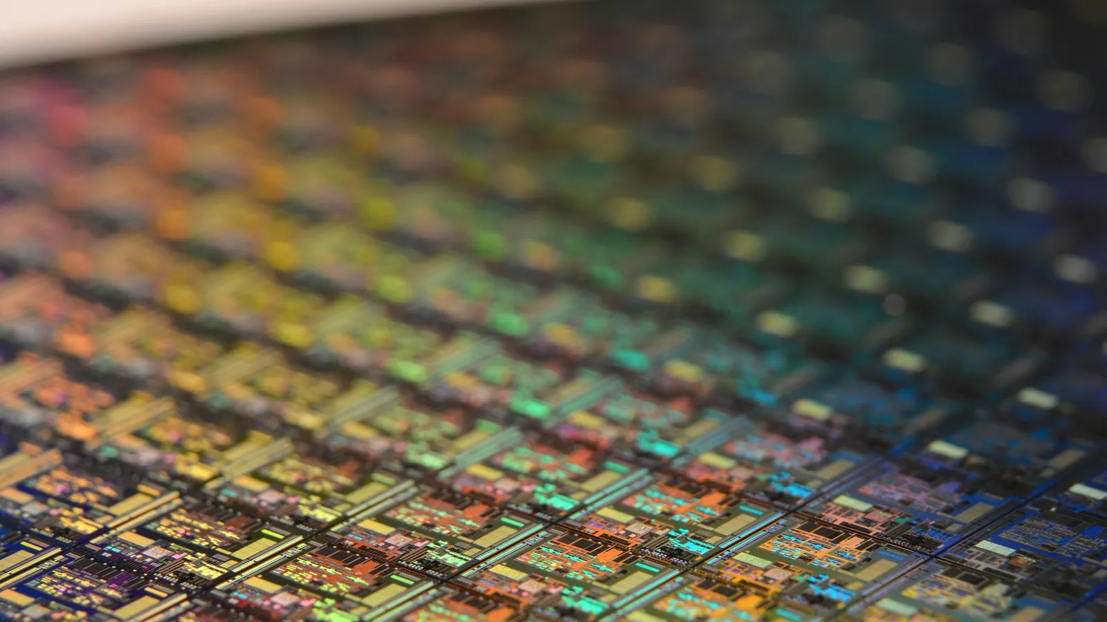 Rows of chips on a silicon wafer catching rainbow light