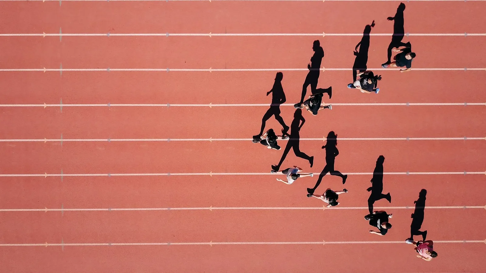 Runners on a red athletics track seen from above