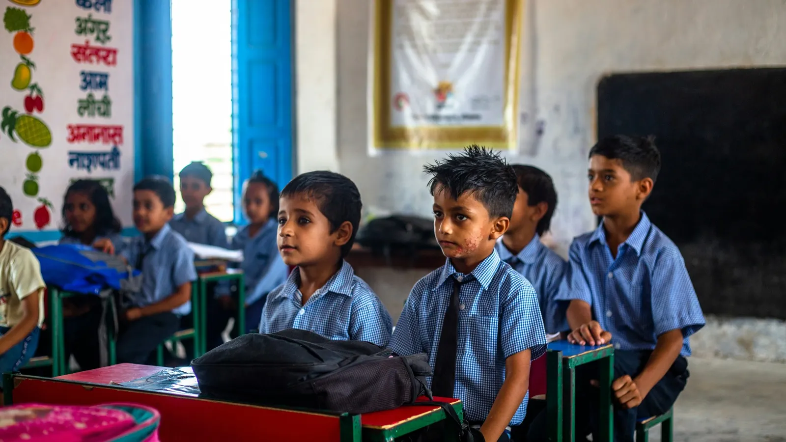 Schoolchildren in blue uniforms sitting at desks in a classroom