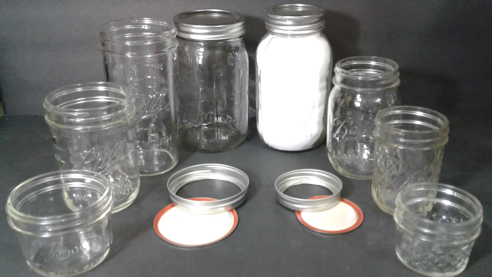 Seven glass Mason jars in a row from largest to smallest