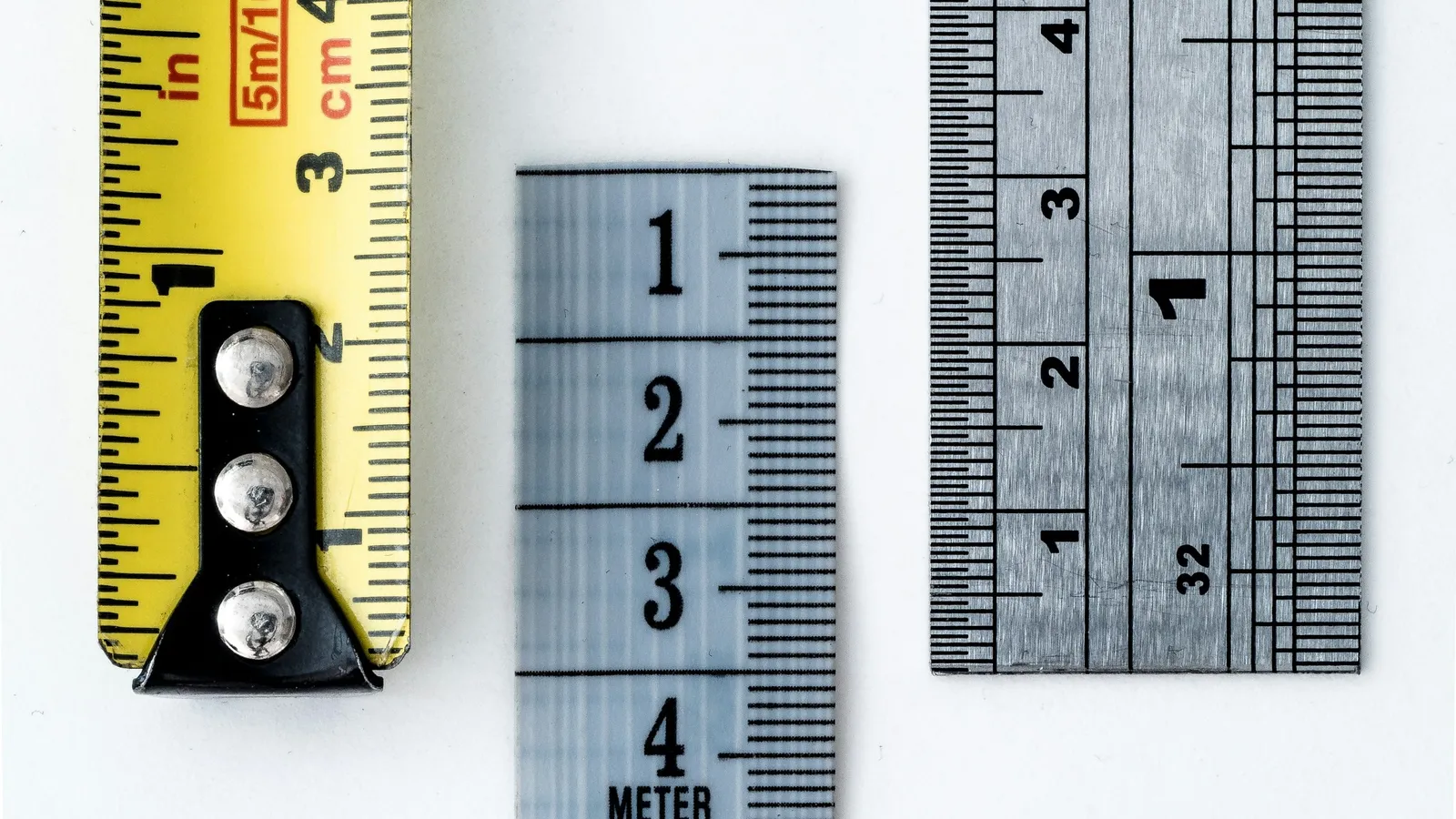 Several measuring tapes and rulers laid side by side