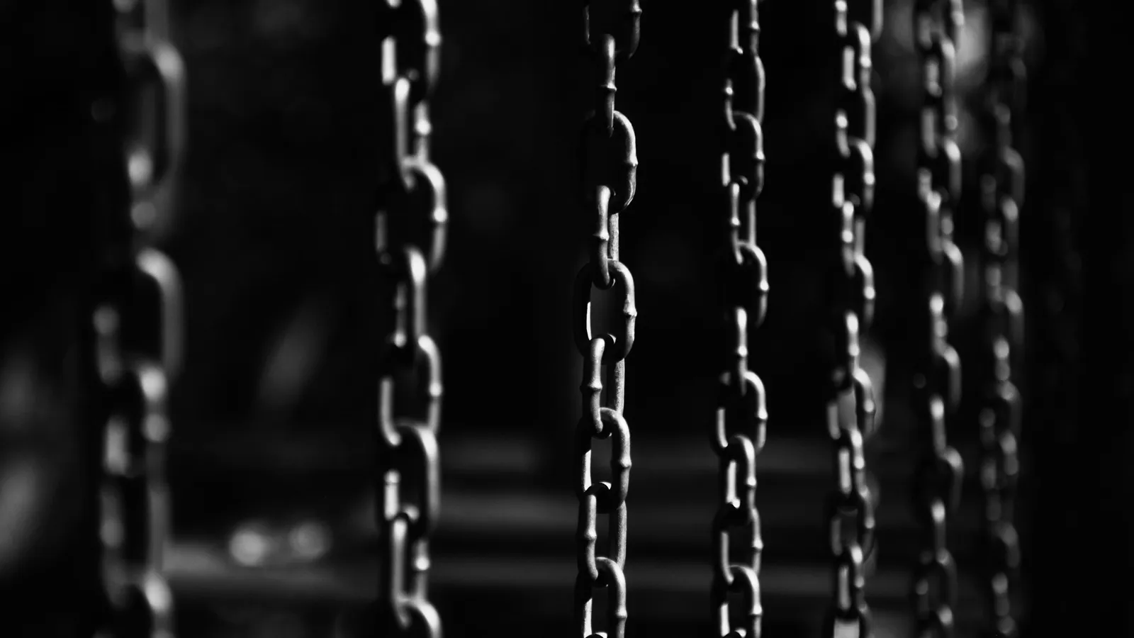 Several metal chains hanging straight down in the dark