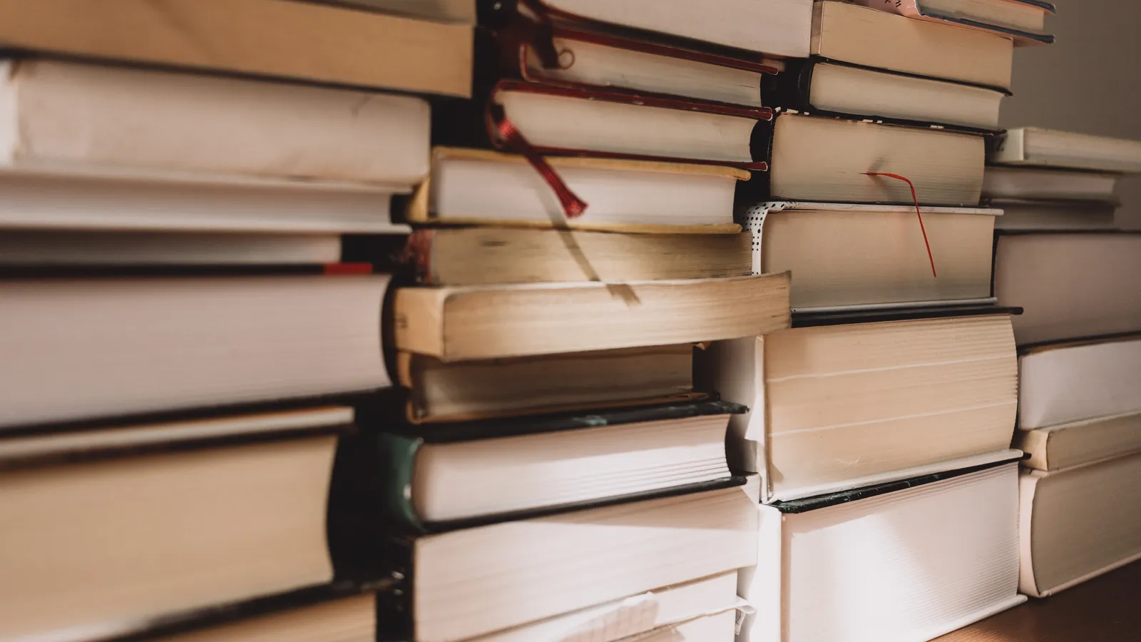 Several tall stacks of thick books on a wooden surface