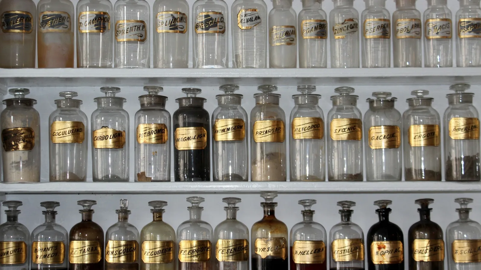 Shelves of old glass apothecary bottles