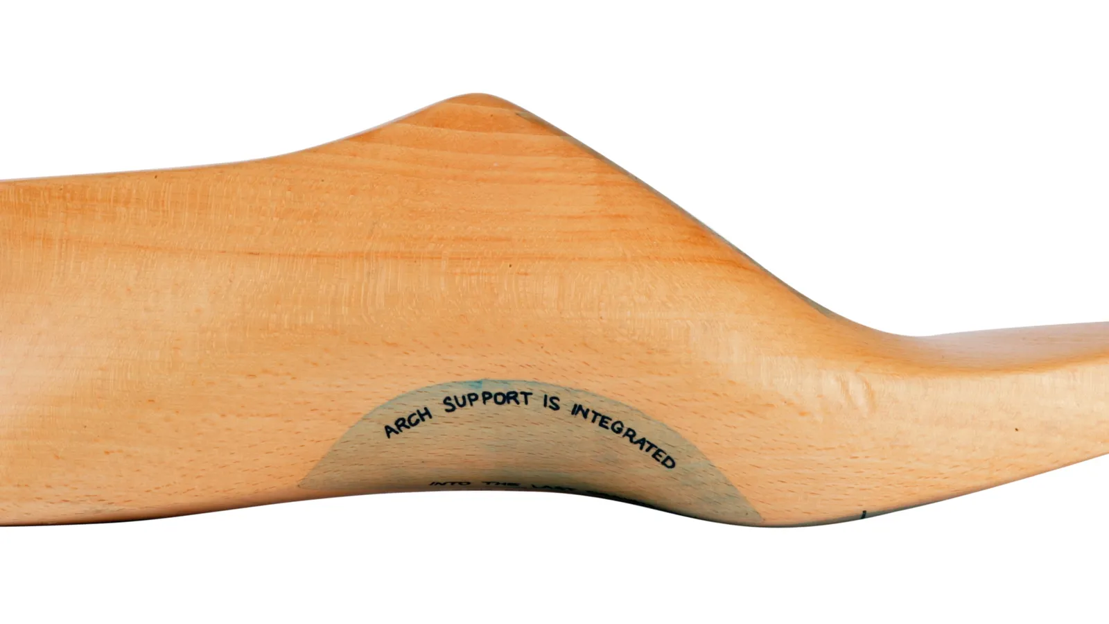 Side view of a pale wooden shoe last with a marked arch support area