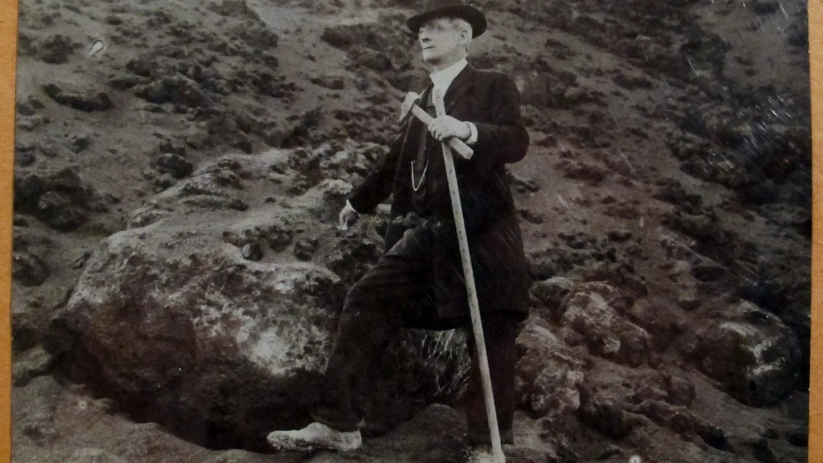 Signed photograph of Giuseppe Mercalli in a hat with a long staff on volcanic rock