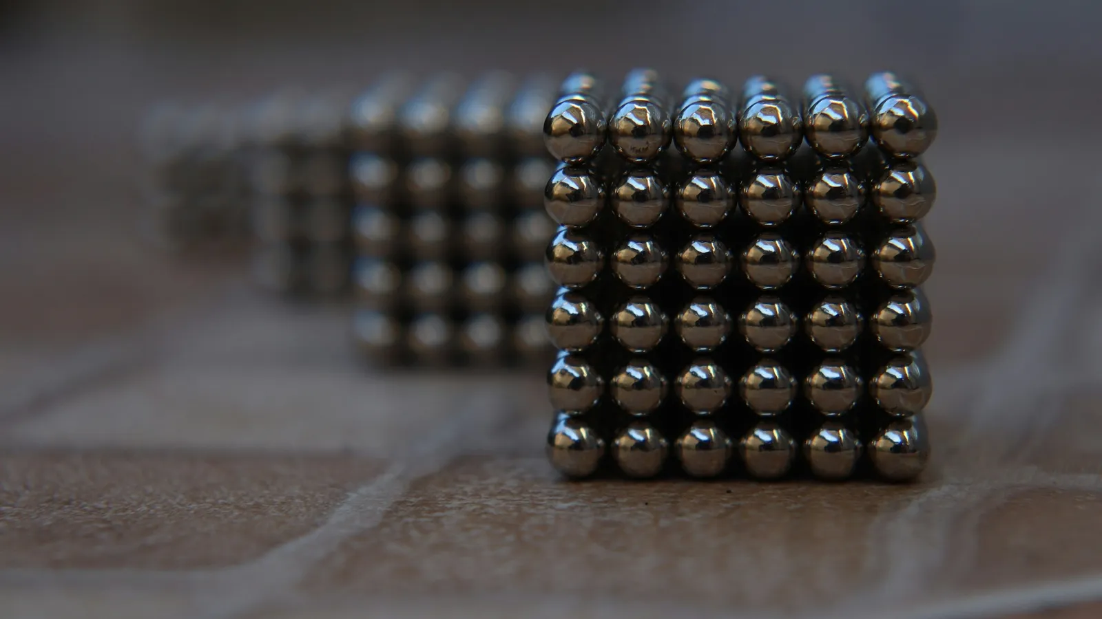 Small spherical magnets stuck together in a cube on a table