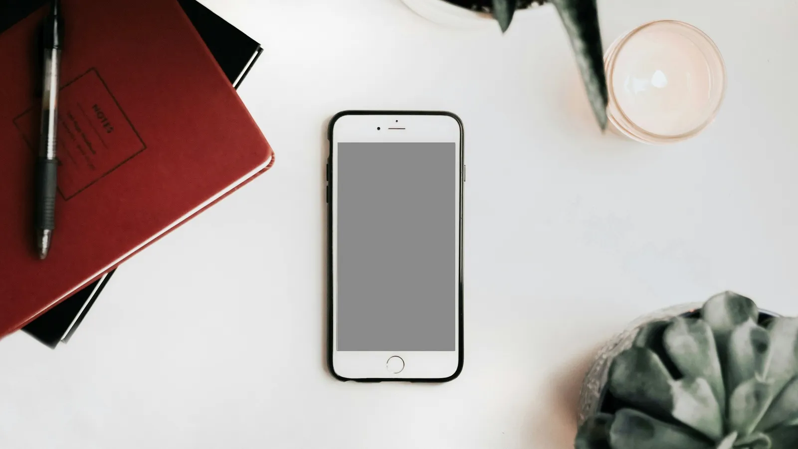 Smartphone lying on a desk next to a notebook