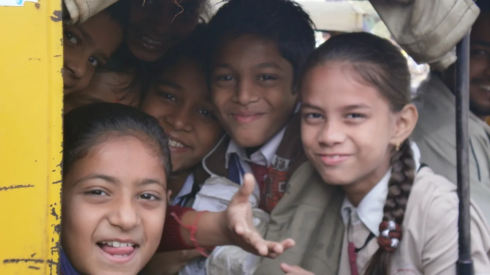 Smiling Indian schoolchildren in uniform crowded together in an auto-rickshaw