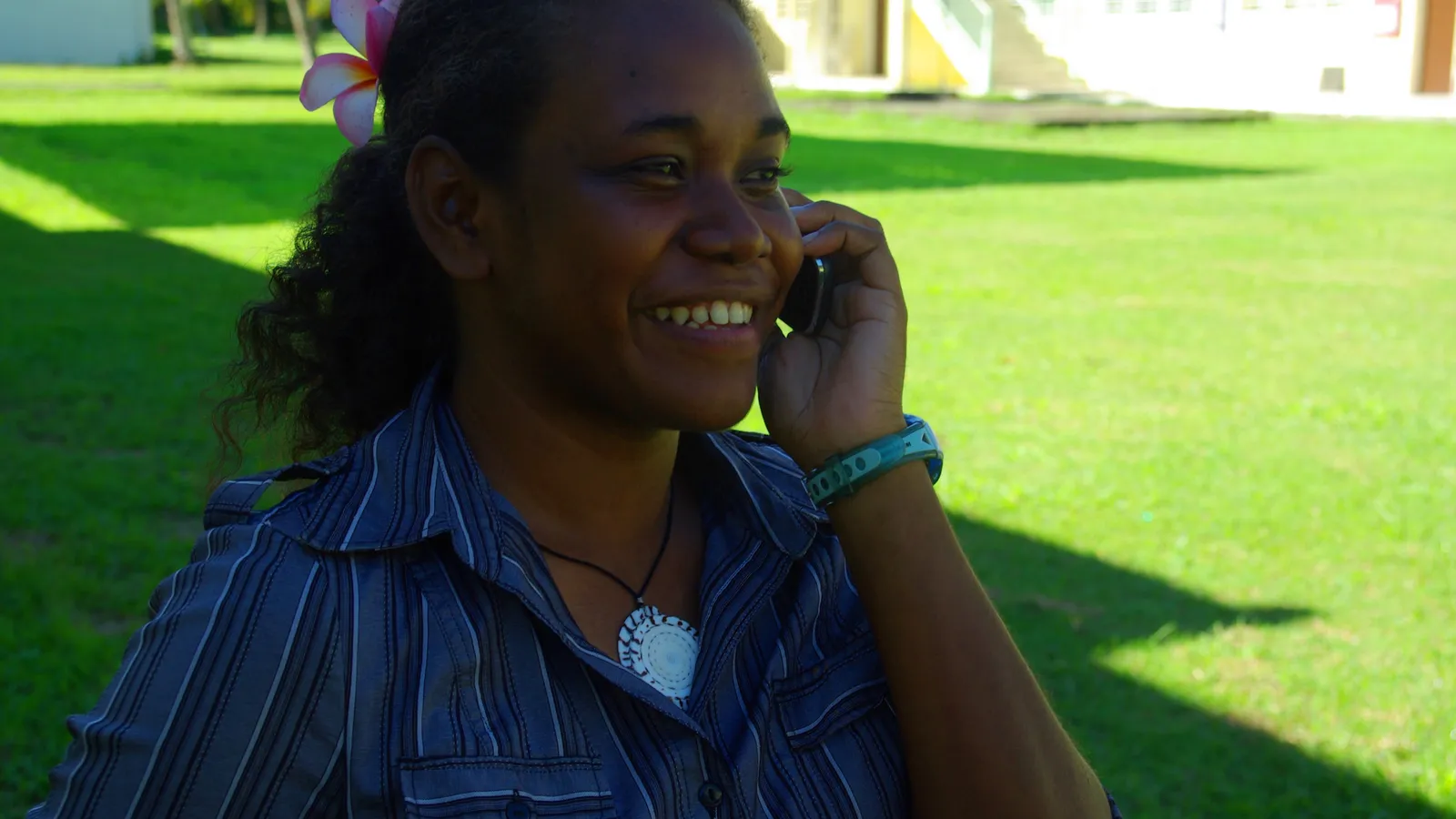 Smiling young woman talking on a mobile phone on a sunny lawn
