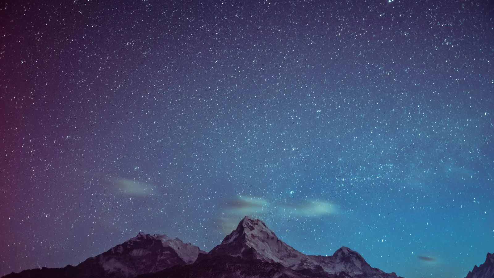 Snow-capped mountain peaks under a starry night sky