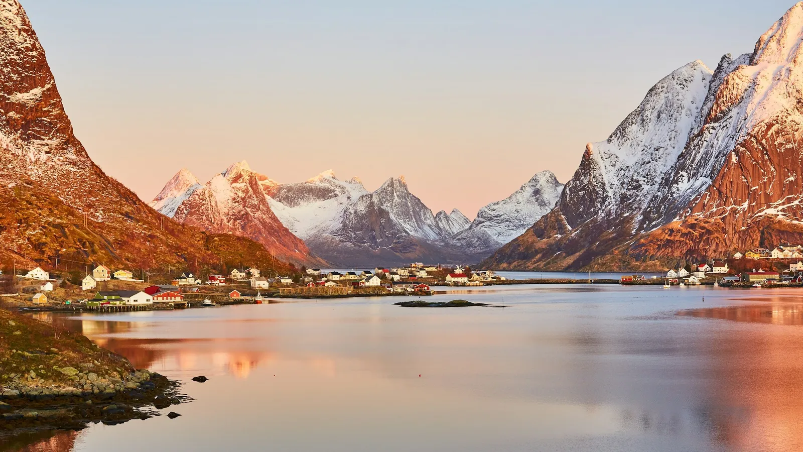 Snowy mountains reflected in a Norwegian fjord at sunset