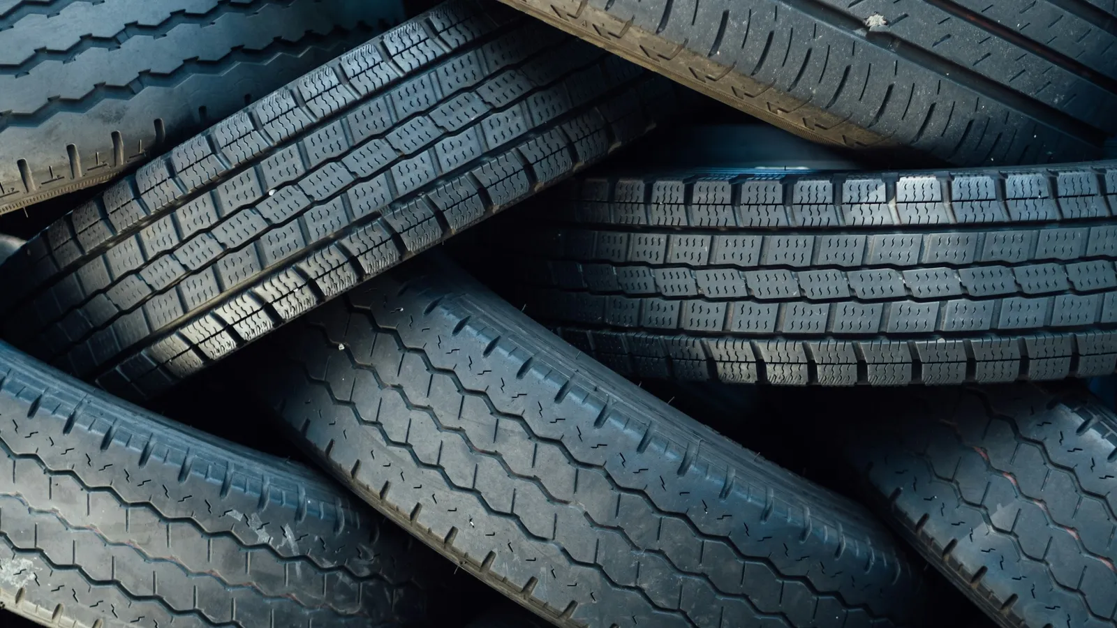 Stacks of black vehicle tyres with deep tread patterns
