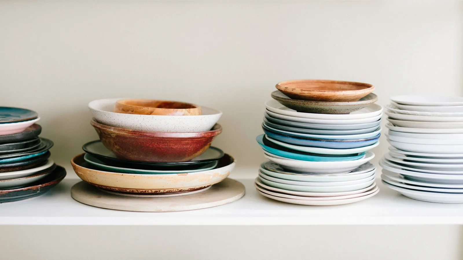 Stacks of plates and bowls on a white shelf