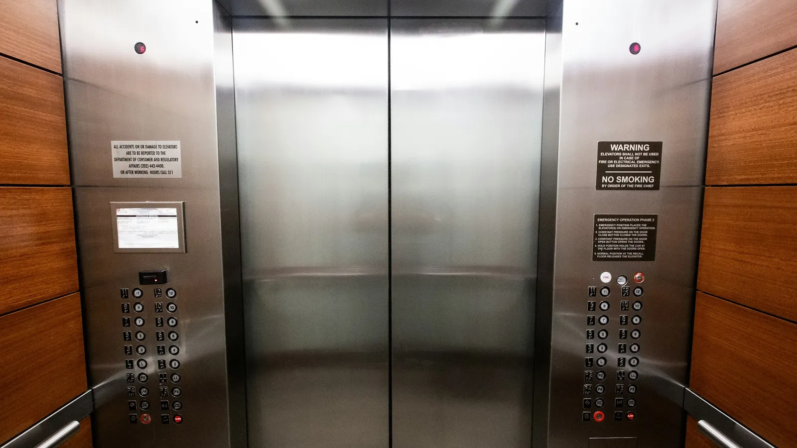 Steel lift doors in a wood-panelled lobby