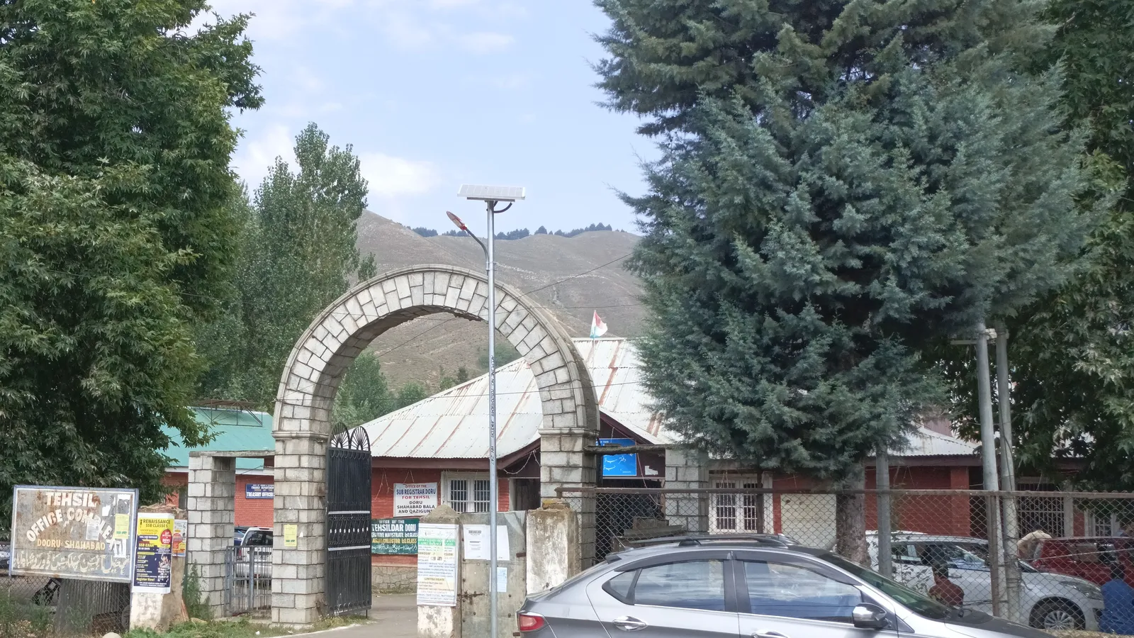 Stone arch gateway to the Tehsil Office Complex in Dooru, Jammu and Kashmir, with a car parked outside
