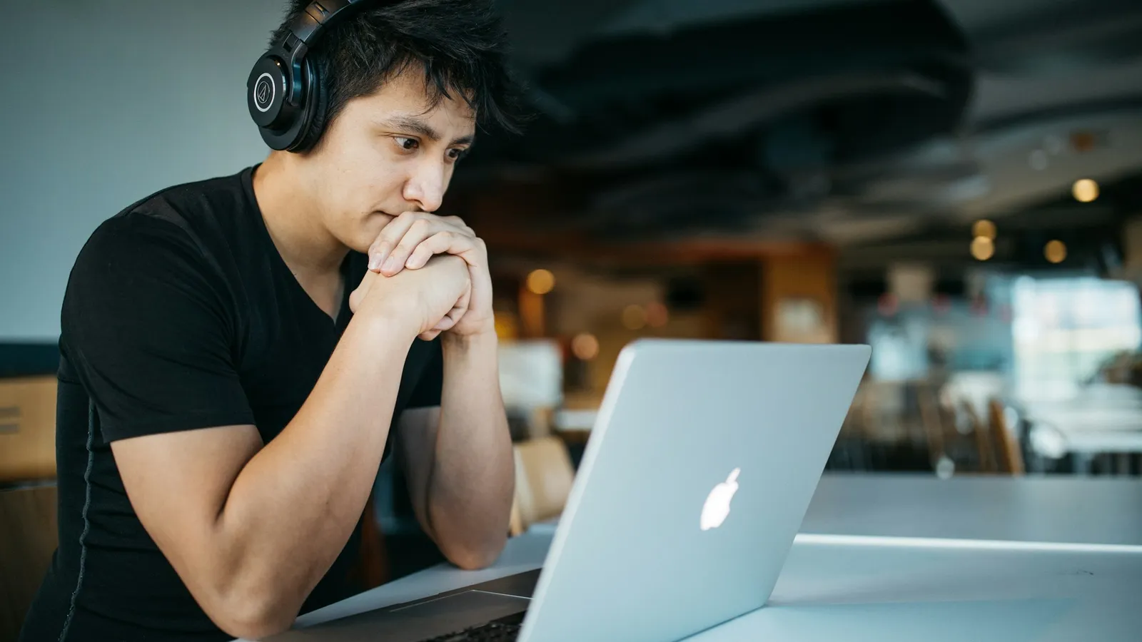 Student wearing headphones thinking hard in front of a laptop