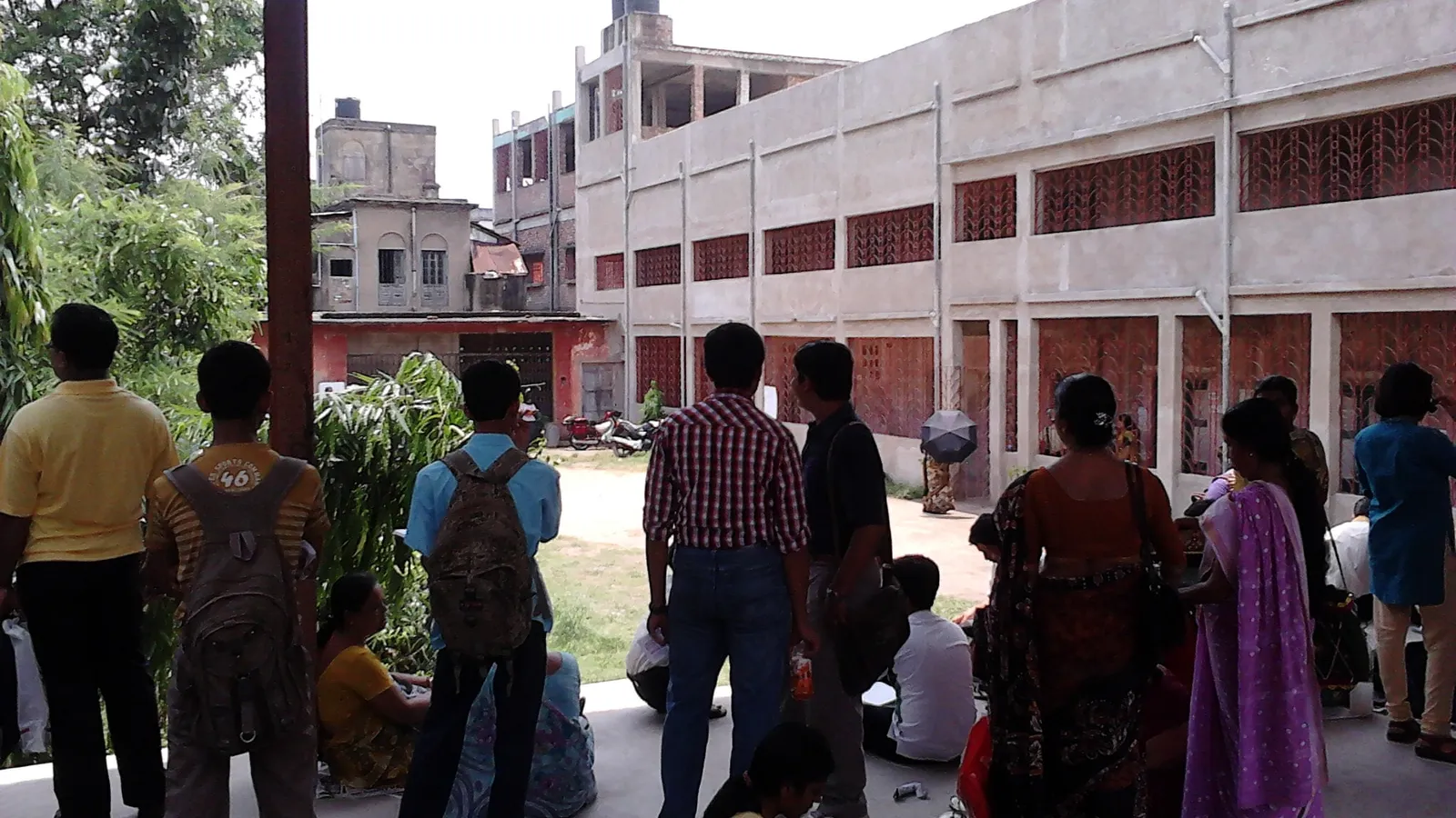 Students and parents waiting in a covered courtyard outside an exam centre